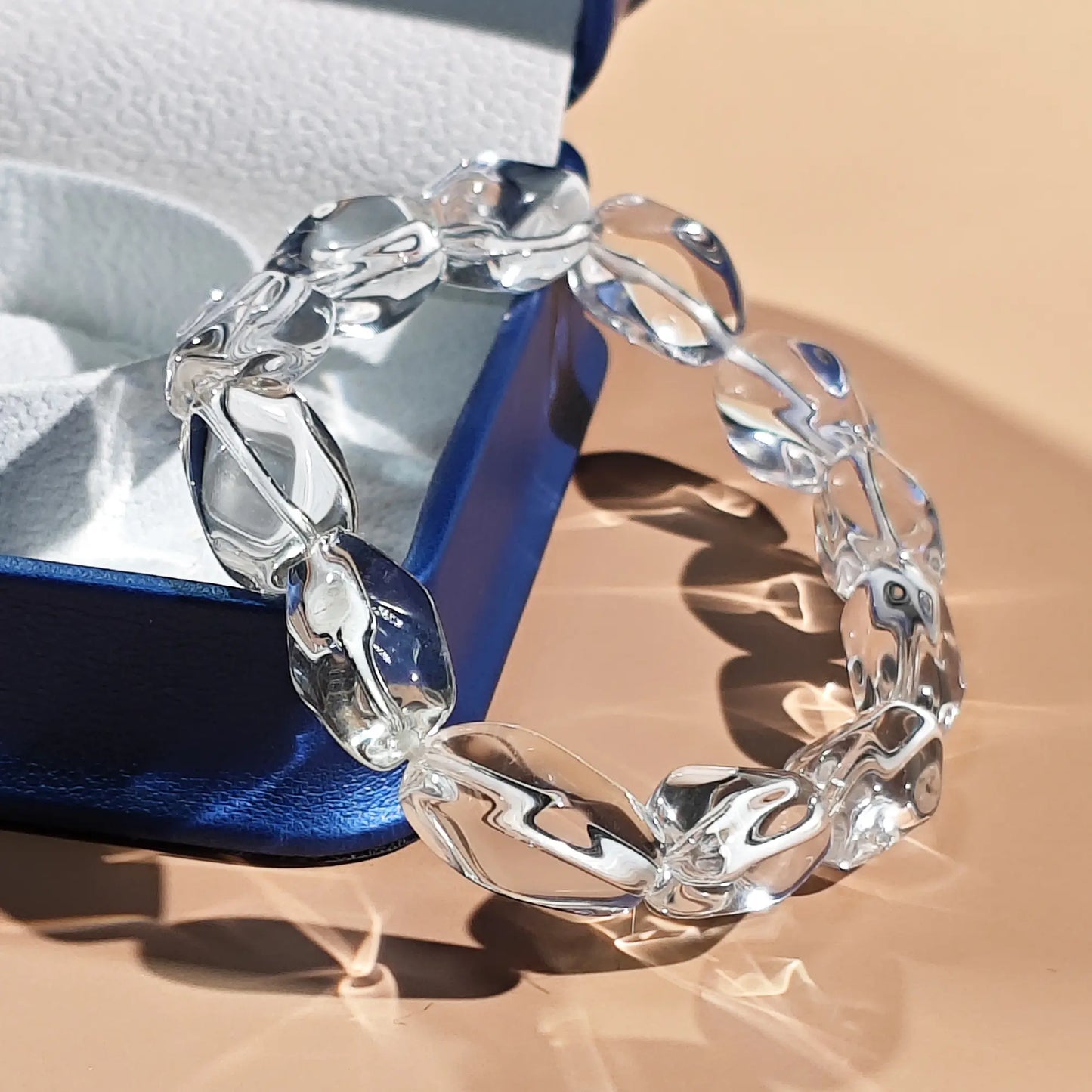 Clear bracelet on a blue and silver box with a beige background