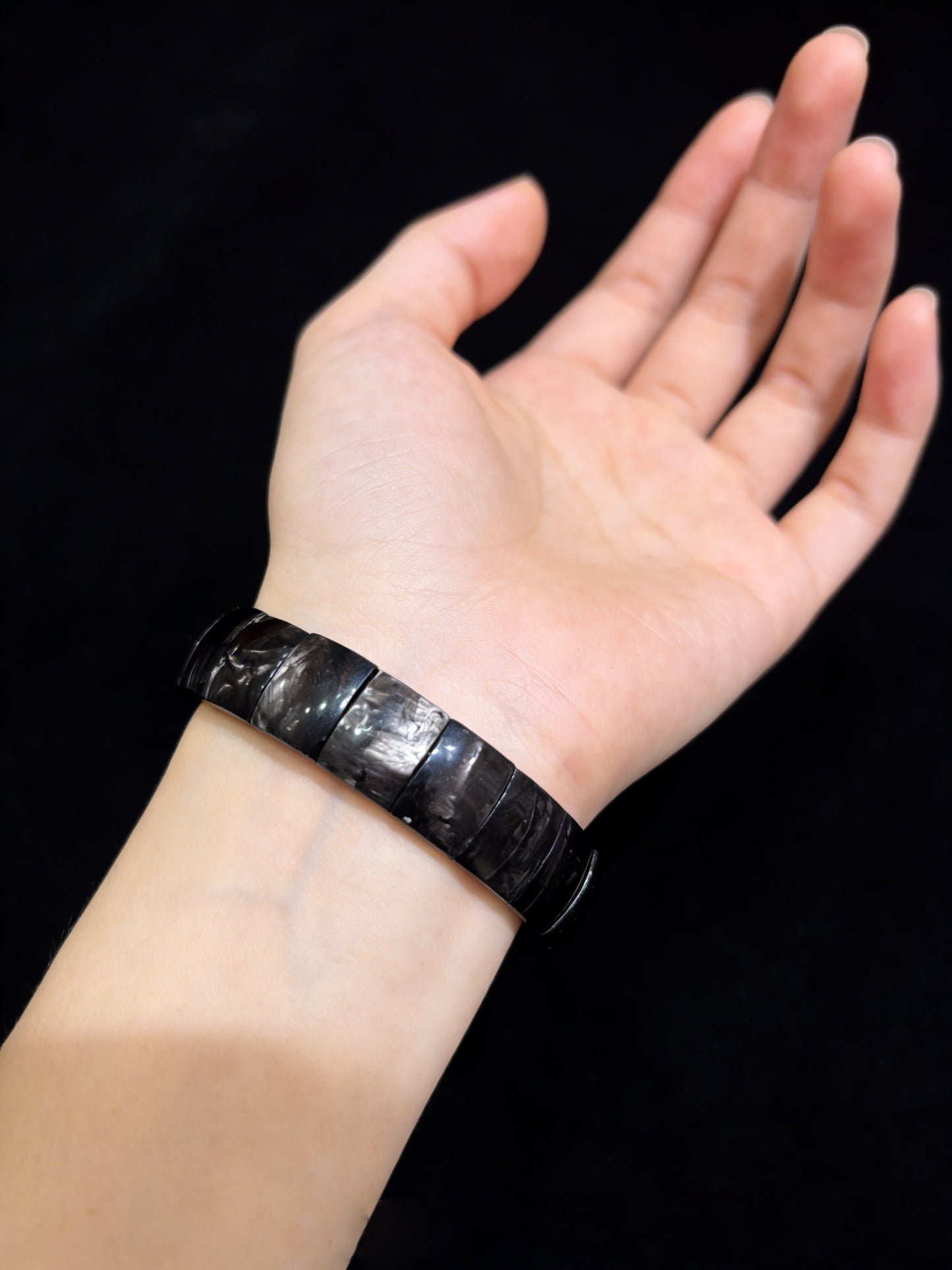 Natural hypersthene bracelet on wrist under soft light; silver streaks catch glow, symbolizing inner insight and calm focus