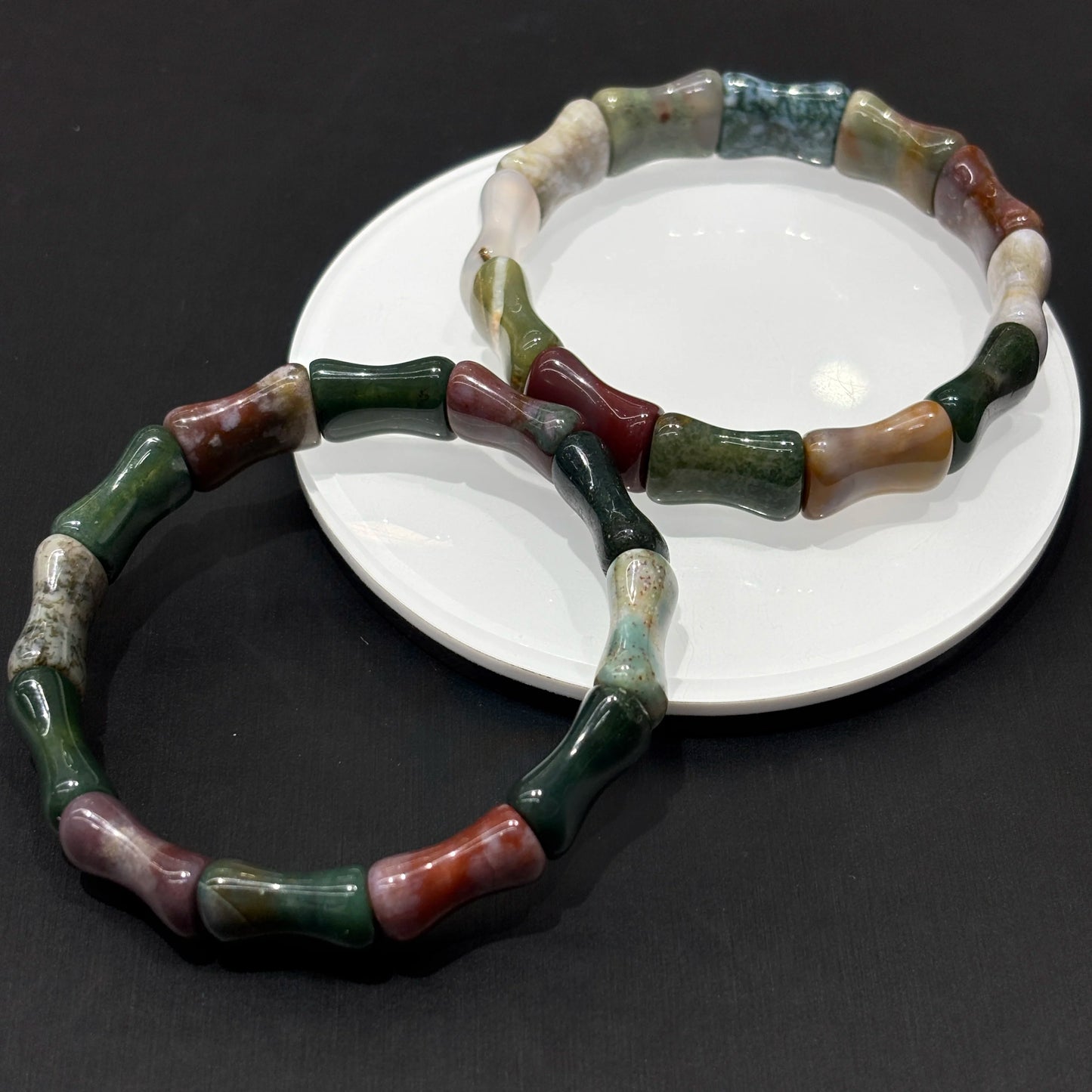 Natural ocean jasper beads with green-red-white-grey banding under soft light; evokes emotional balance and gentle resilience
