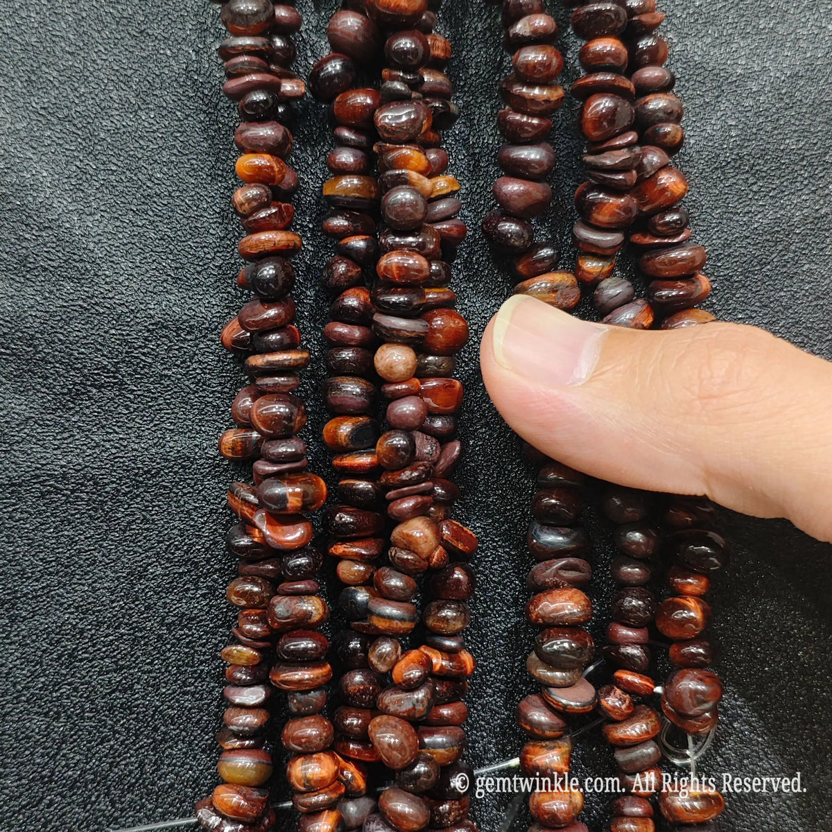 Detailed view of 75cm long red tiger eye tumbled chipped gemstone strand for jewelry DIY