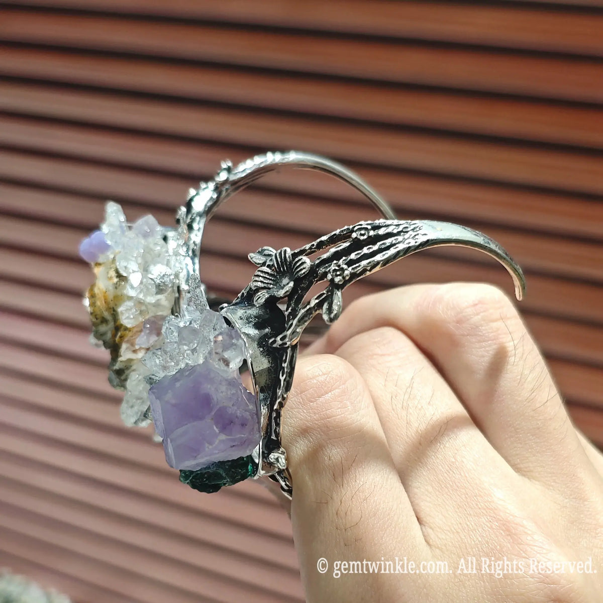 Close up view of raw amethyst points clear quartz clusters and malachite mounted on antique metal cuff