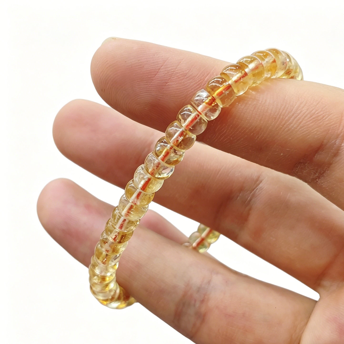 Gentle touch on citrine tablet bead—revealing smooth finish, subtle internal texture, and luminous color depth