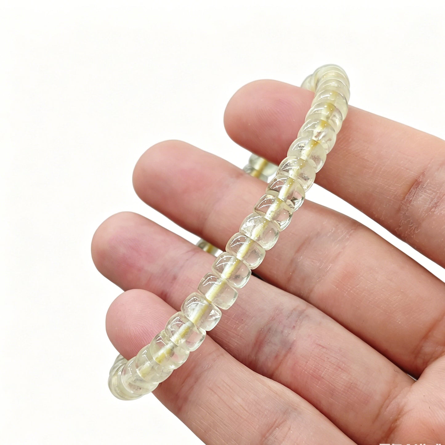 Gentle touch on lemon citrine tablet bead—revealing smooth finish, subtle internal texture, and luminous light-yellow color