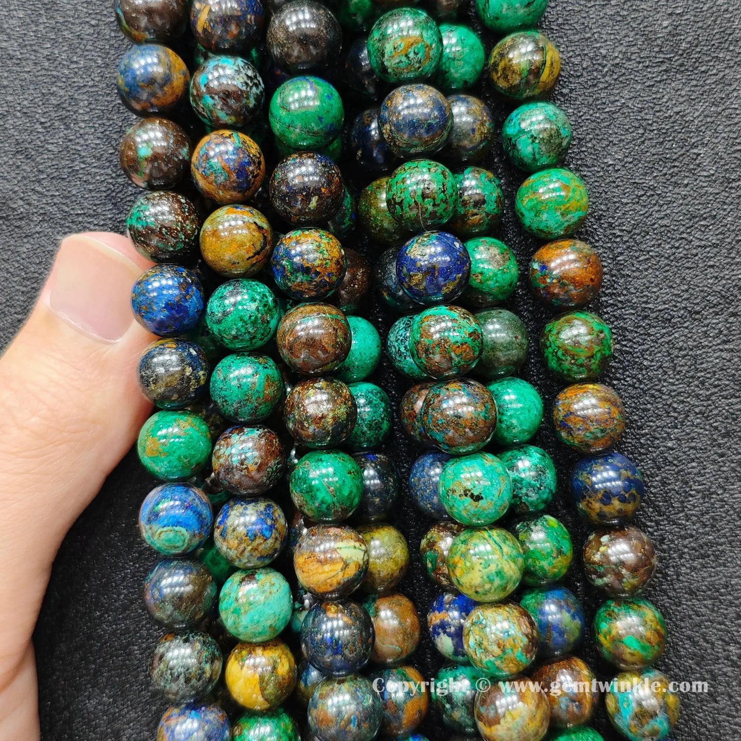 Close up view of natural azurite malachite round beads held on hand for authentic color pattern preview
