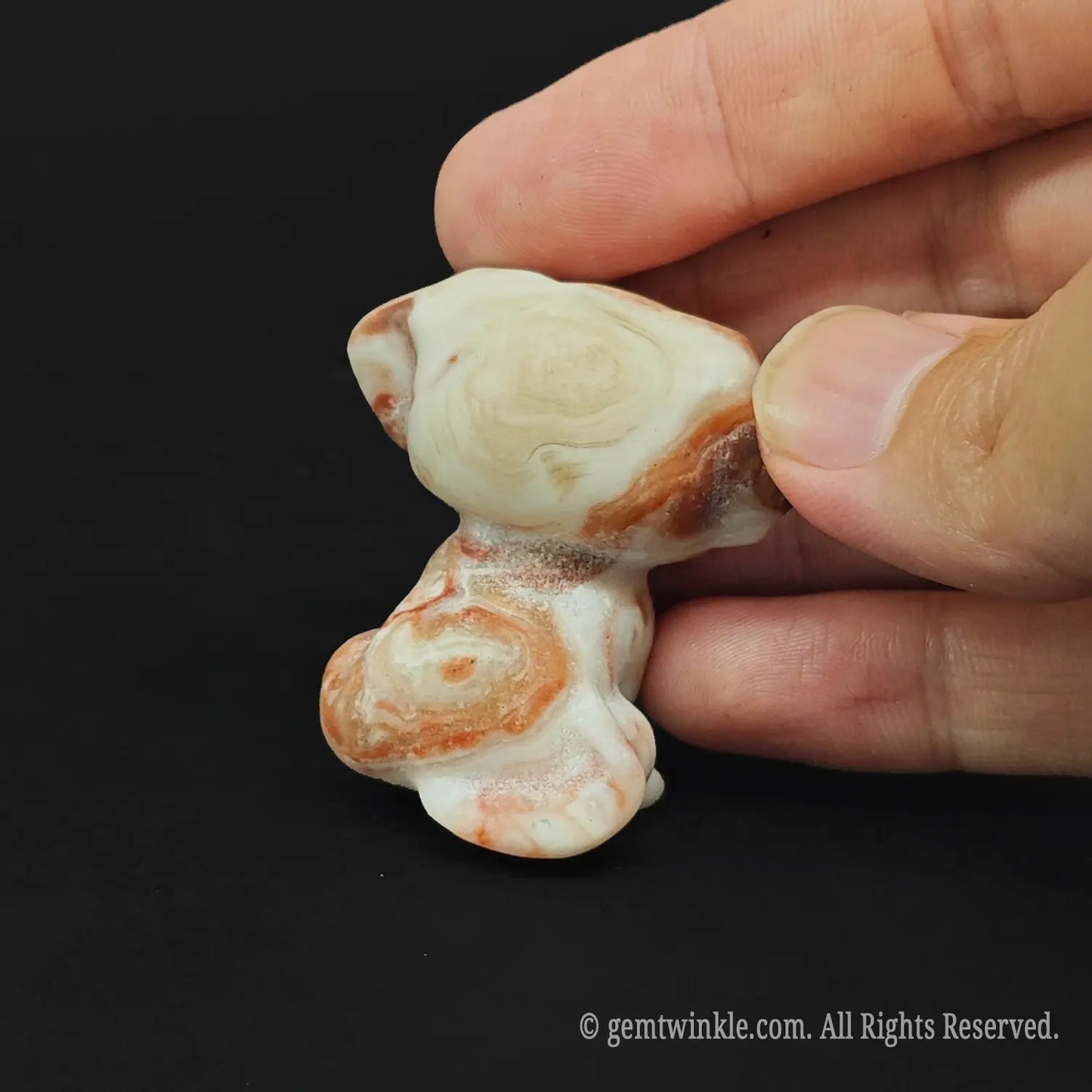 Back and side view of a silk vein mineral dog sculpture displaying organic wavy white and orange crystalline lines