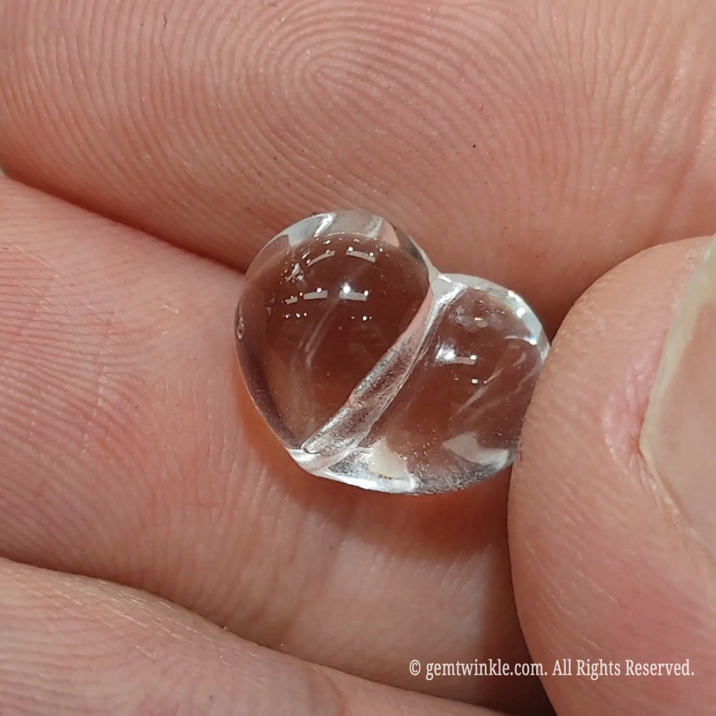 Carved 3d clear quartz heart bead side angle view displaying ice clean crystal transparency and light refraction