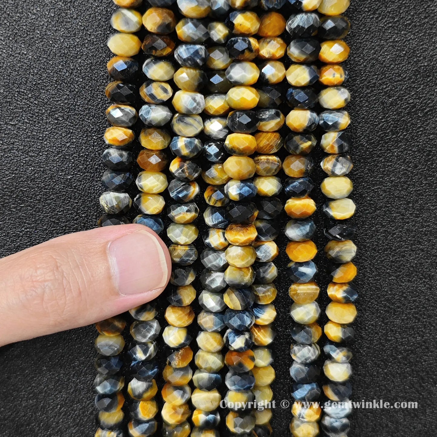 Close up view of 8x5mm fancy tiger eye rondelle beads held on hand for size and chatoyancy preview