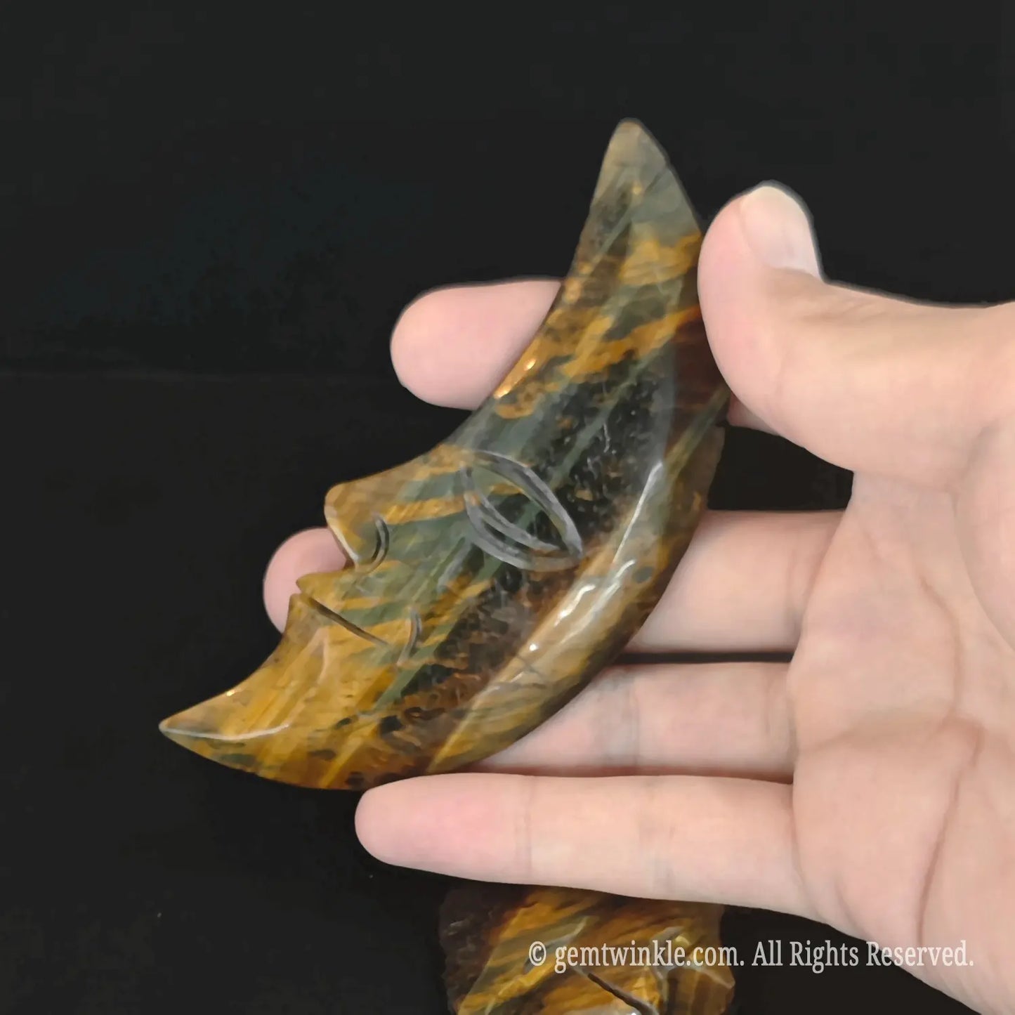Side view of a natural golden striped moon face carving demonstrating thickness and structural details