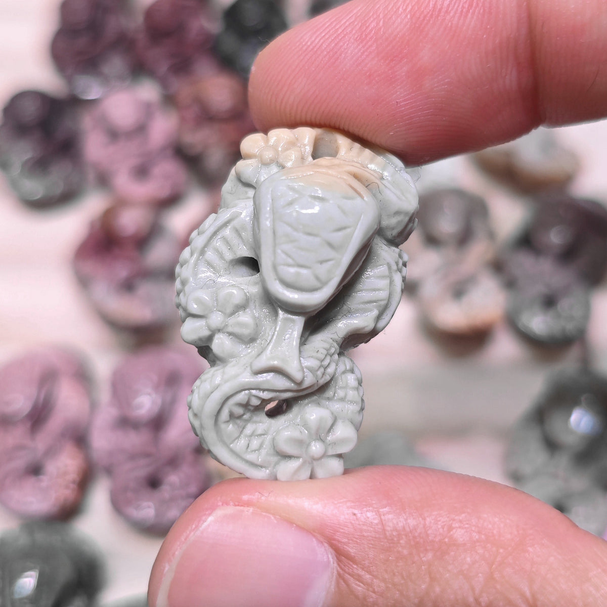 Top down group display of tiny plum blossom snake stone carvings in various natural colors