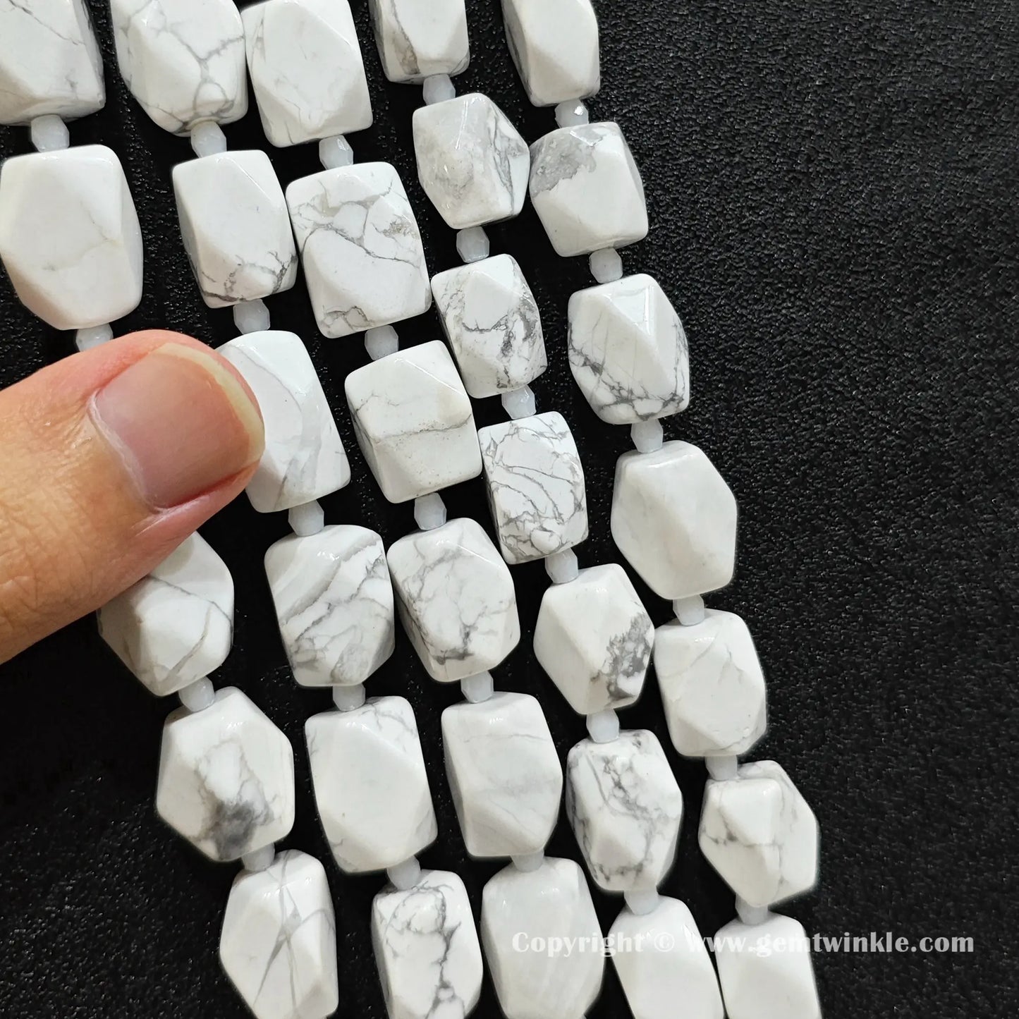 hand held scale preview of 15mm faceted white howlite barrel beads