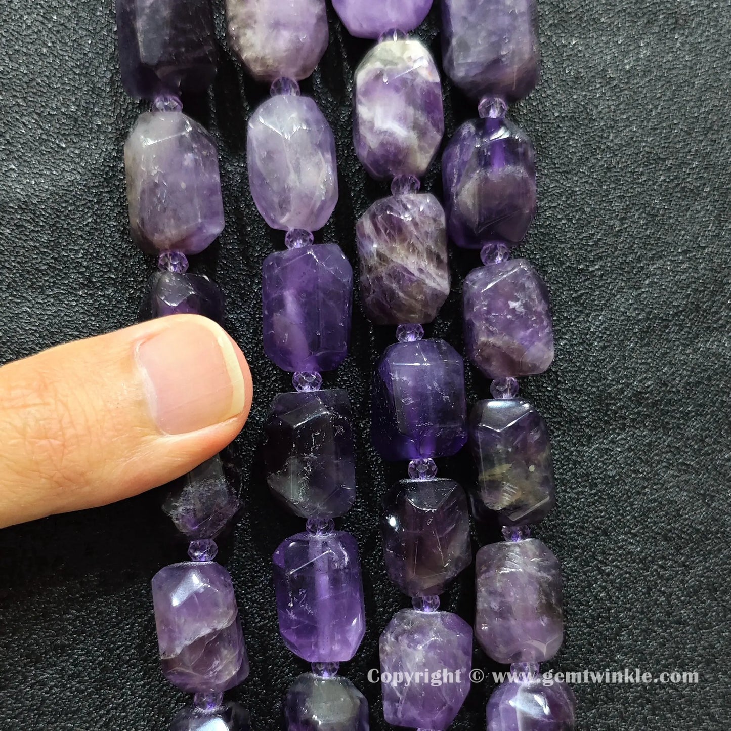 hand holding large purple amethyst faceted barrel beads showing scale and texture
