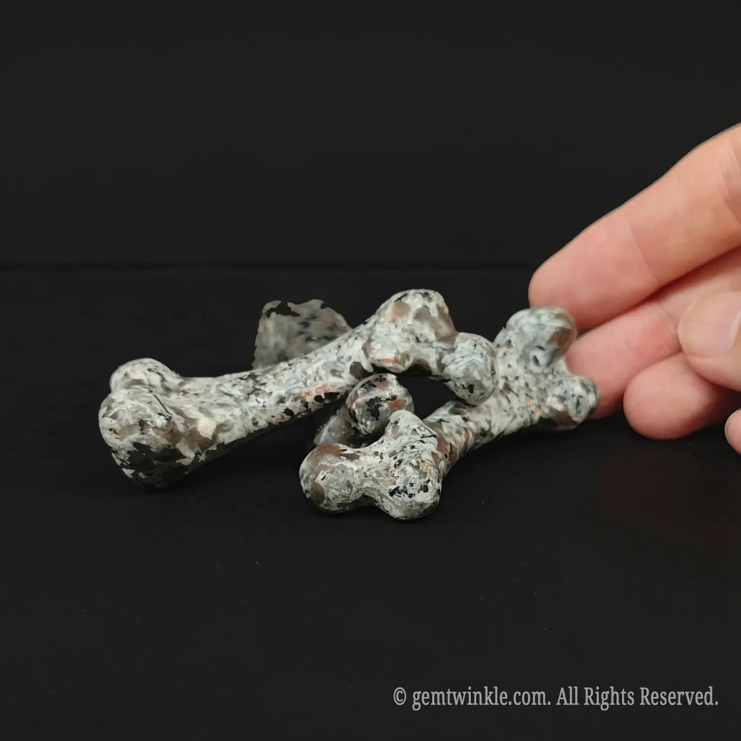 Handheld view of a 6cm natural grey stone bone figurine demonstrating retail scale and smooth finish