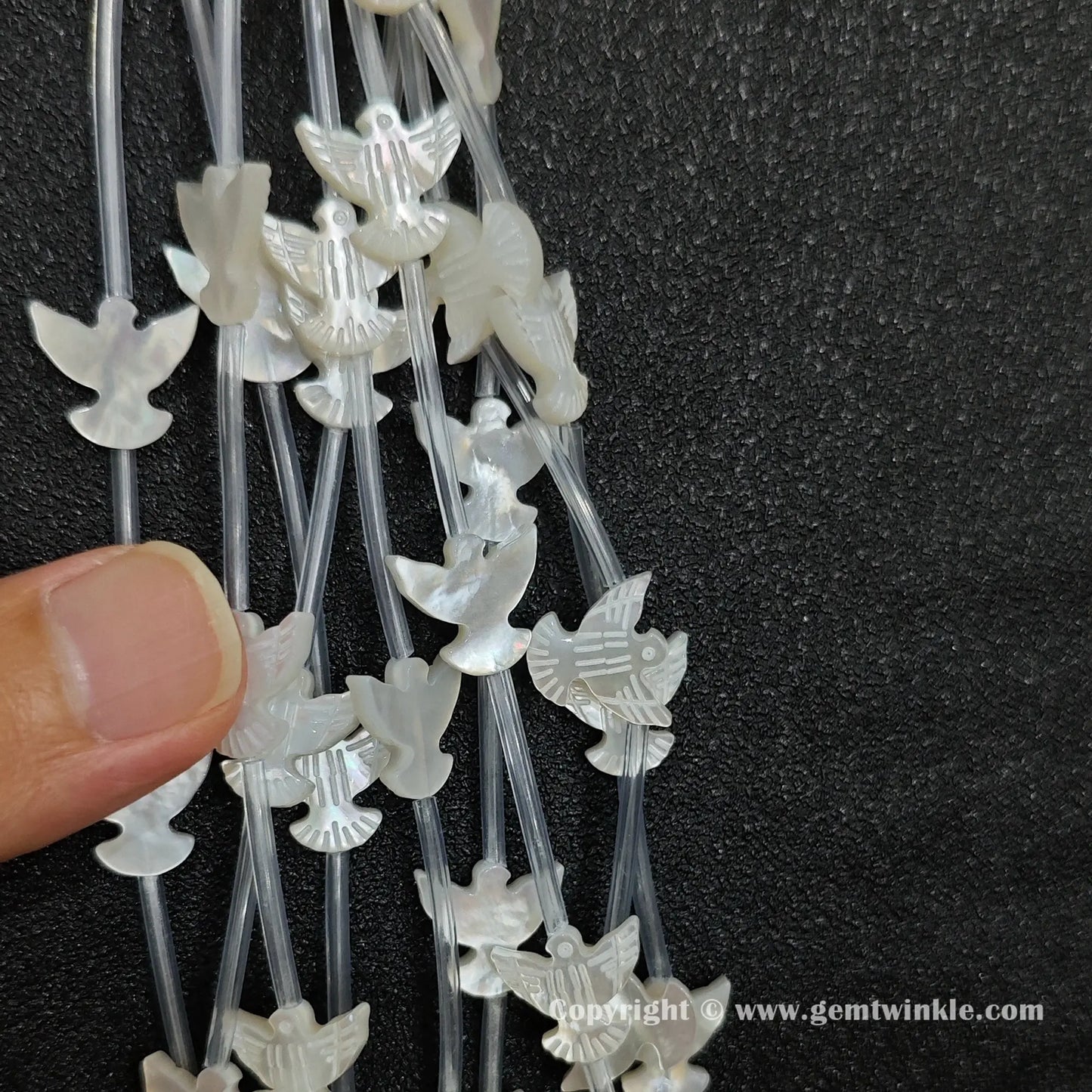 Handheld preview showing 12x14mm white shell peace dove beads in hand
