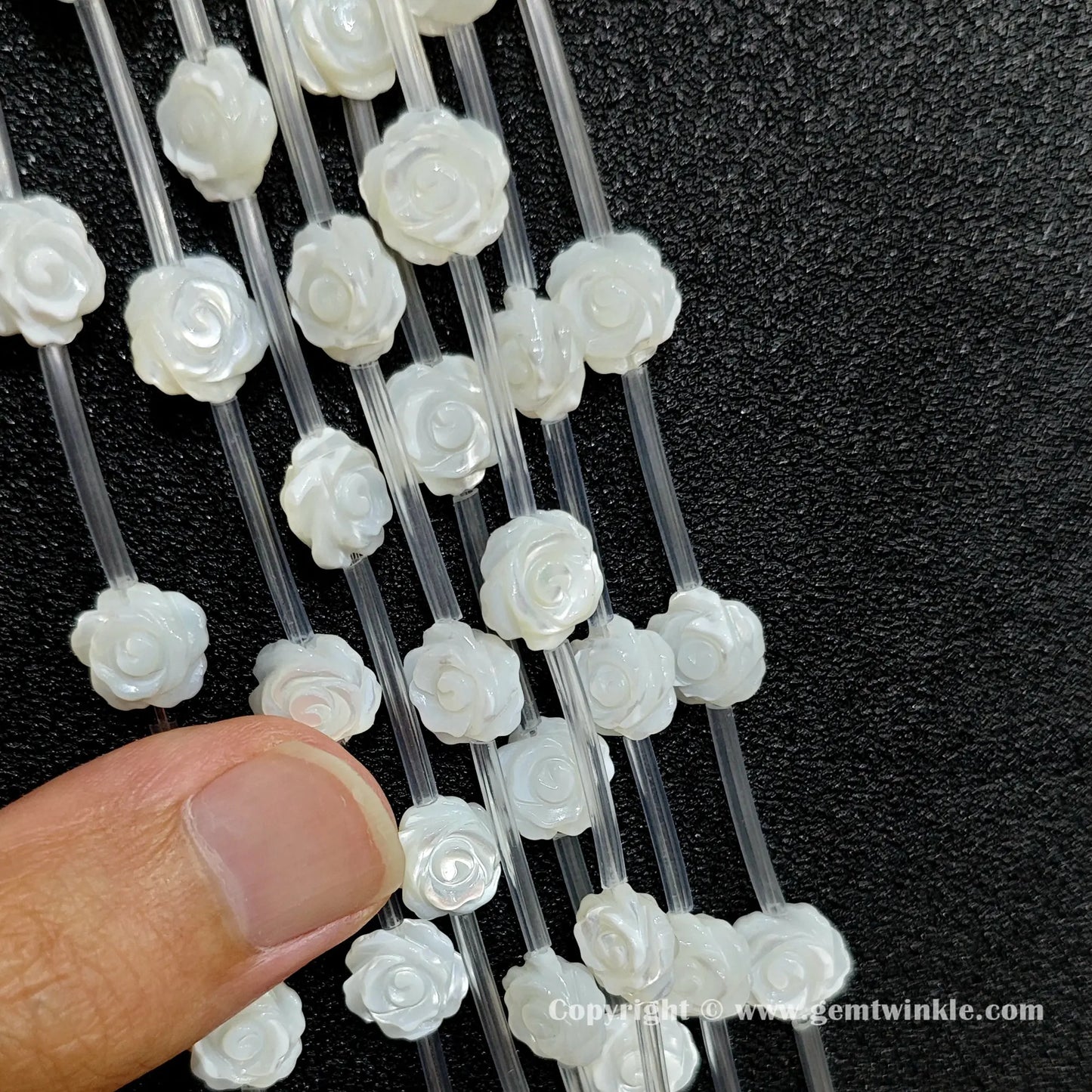 Handheld preview showing white shell rose flower carved beads in hand
