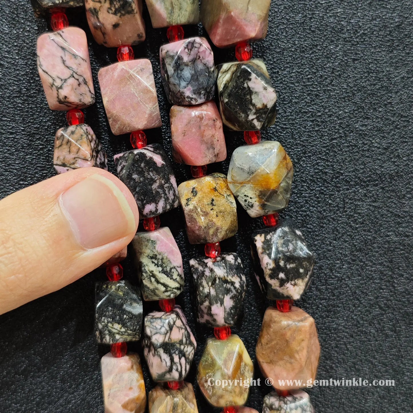 handheld scale view of 15mm faceted black veined rhodonite beads