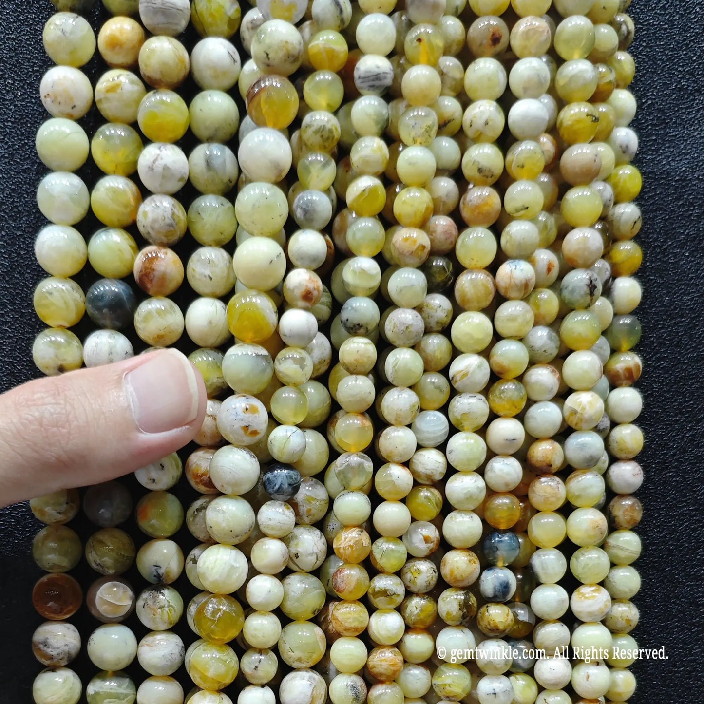 hand holding a massive bundle of high quality gemstone beads in natural yellow opal matrix showing stock volume for boutique retail sourcing