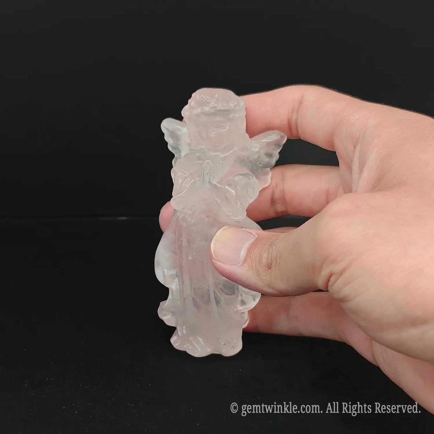 Hand holding an approx 10cm natural pink rose quartz guardian angel carving to display actual physical size and glassy shine for wholesale buyers