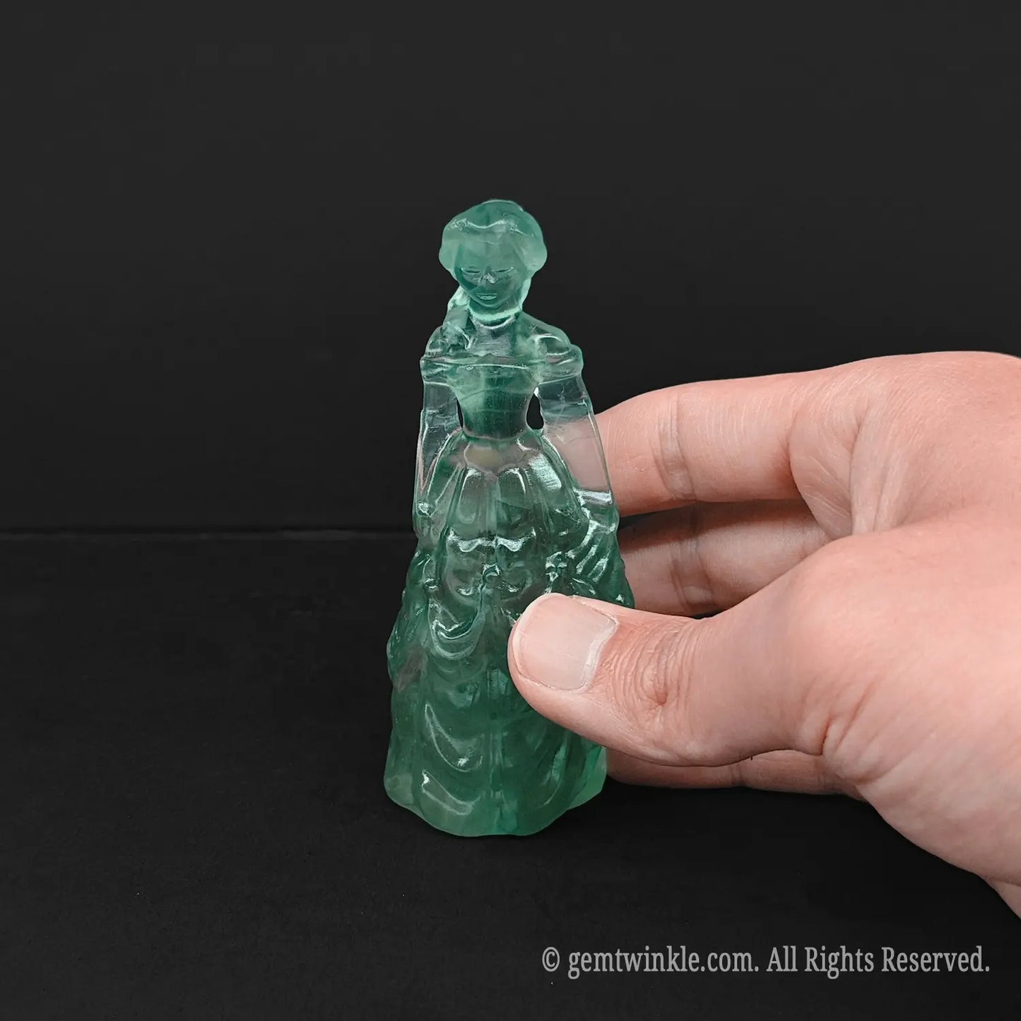 Hand holding an approx 10cm (4 inches) clear green fluorite princess statue to display its high clarity and actual size for wholesale buyers