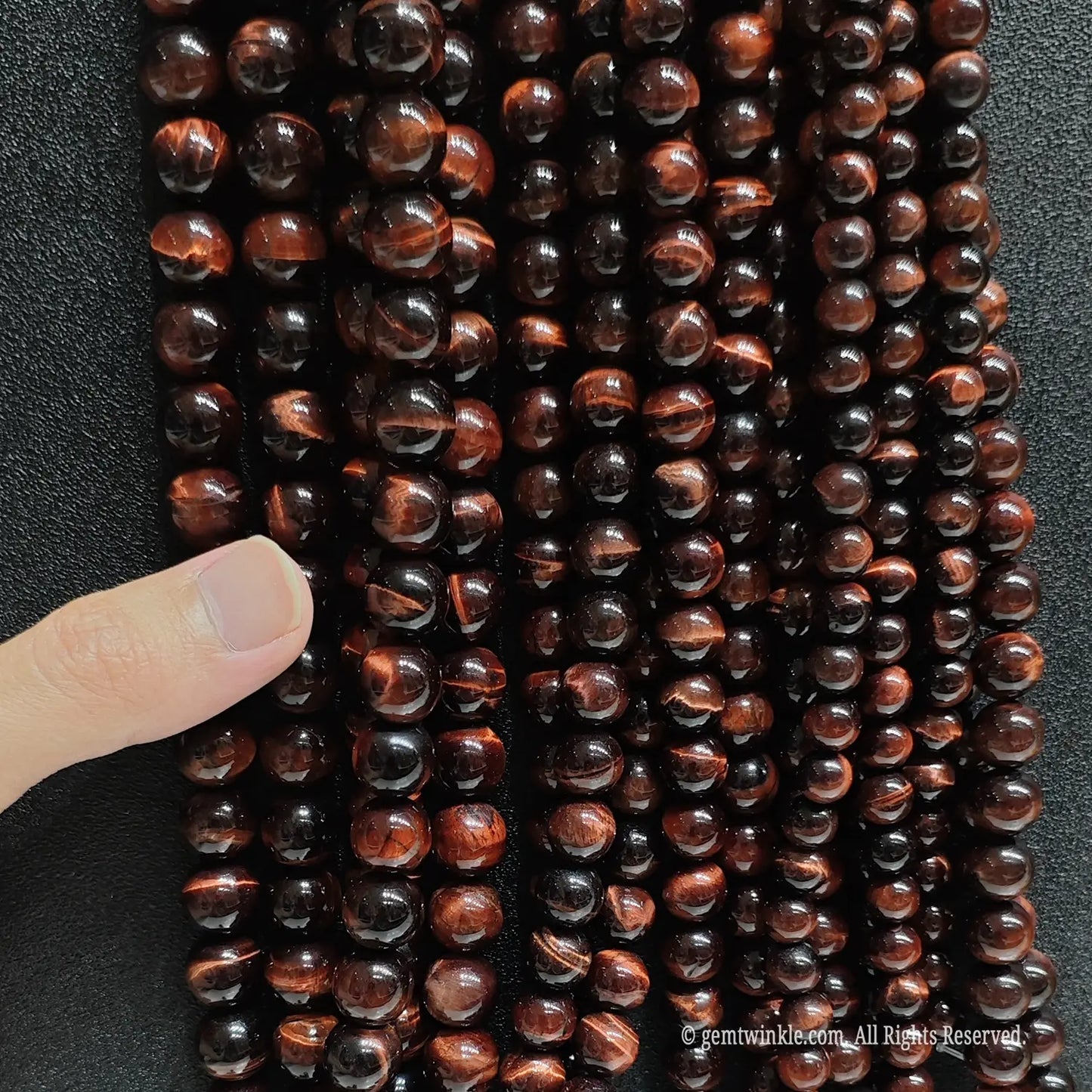 Assorted 4mm to 20mm red tigers eye round beads on black background