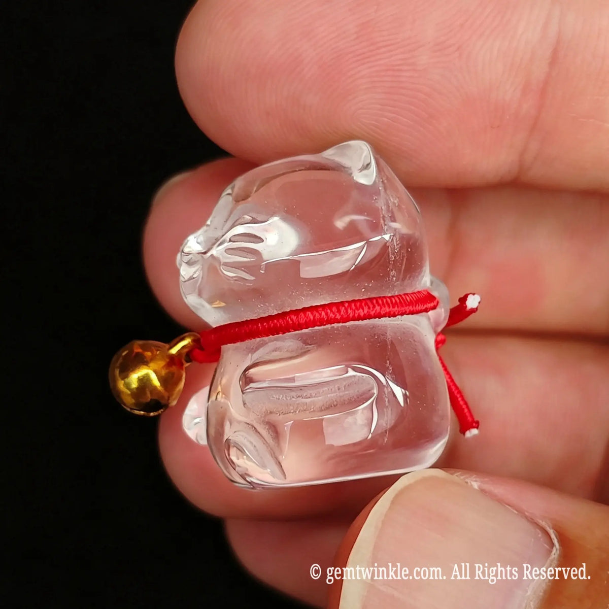 Close up preview of mini clear quartz fortune cat carving highlighting detailed facial features and bell