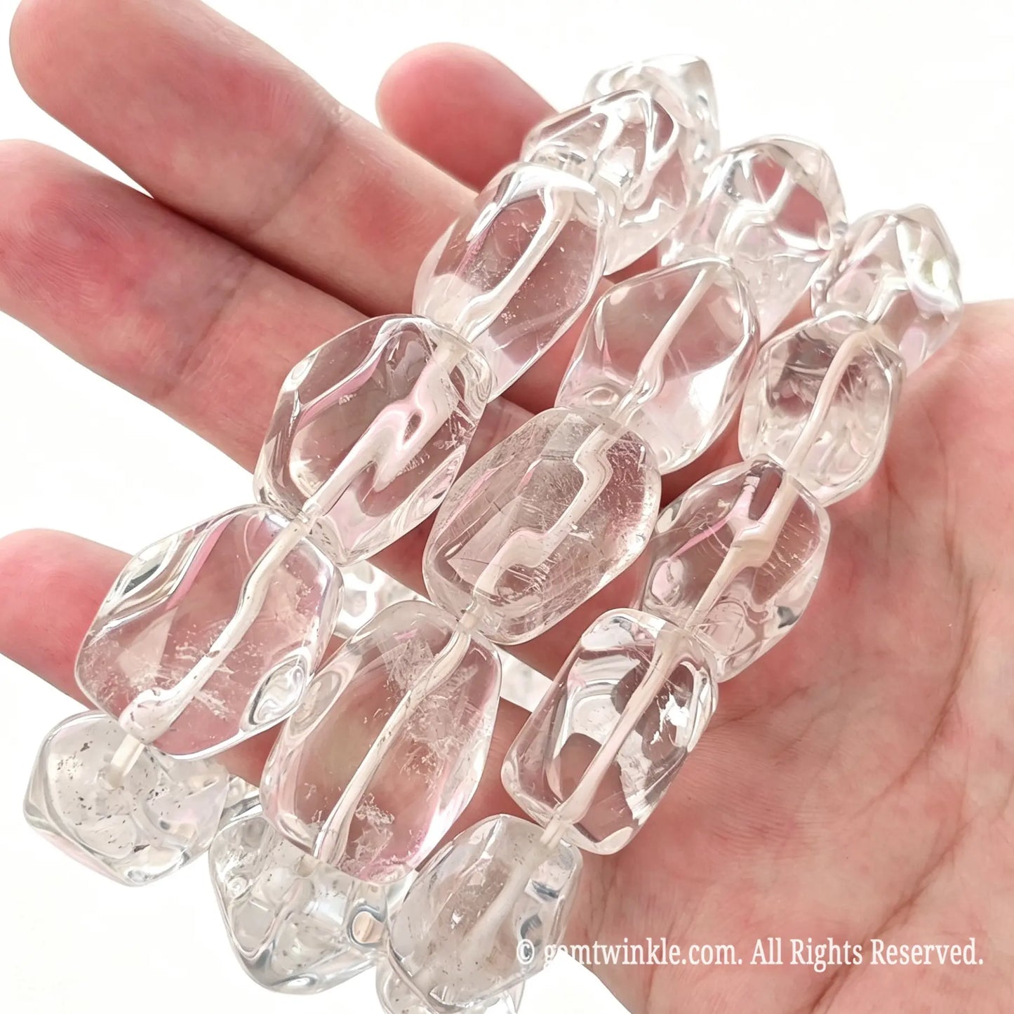 Handheld angle view of chunky clear quartz freeform bead stretch bracelets showing smooth polish and rich internal ice fissures