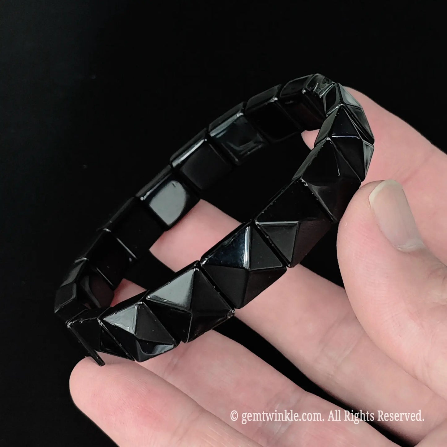 Full view of natural black obsidian 11mm geometric pyramid bracelet resting in hand showcasing high polish reflections