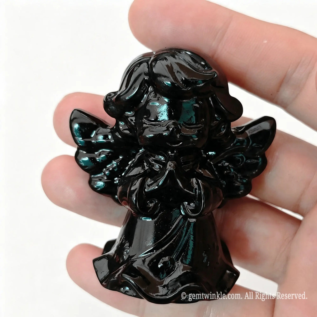 Single natural black obsidian praying angel statue 6cm height held in hand showing polished dark surface