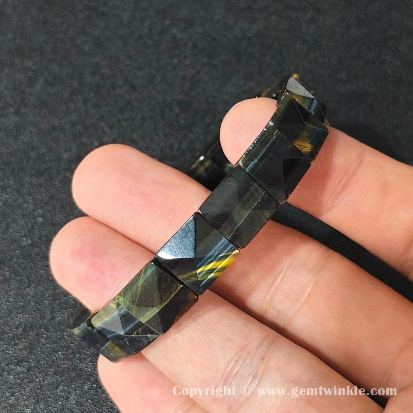 close up view of blue tigers eye plate stretch bracelet showing internal elastic cord and gloss finish
