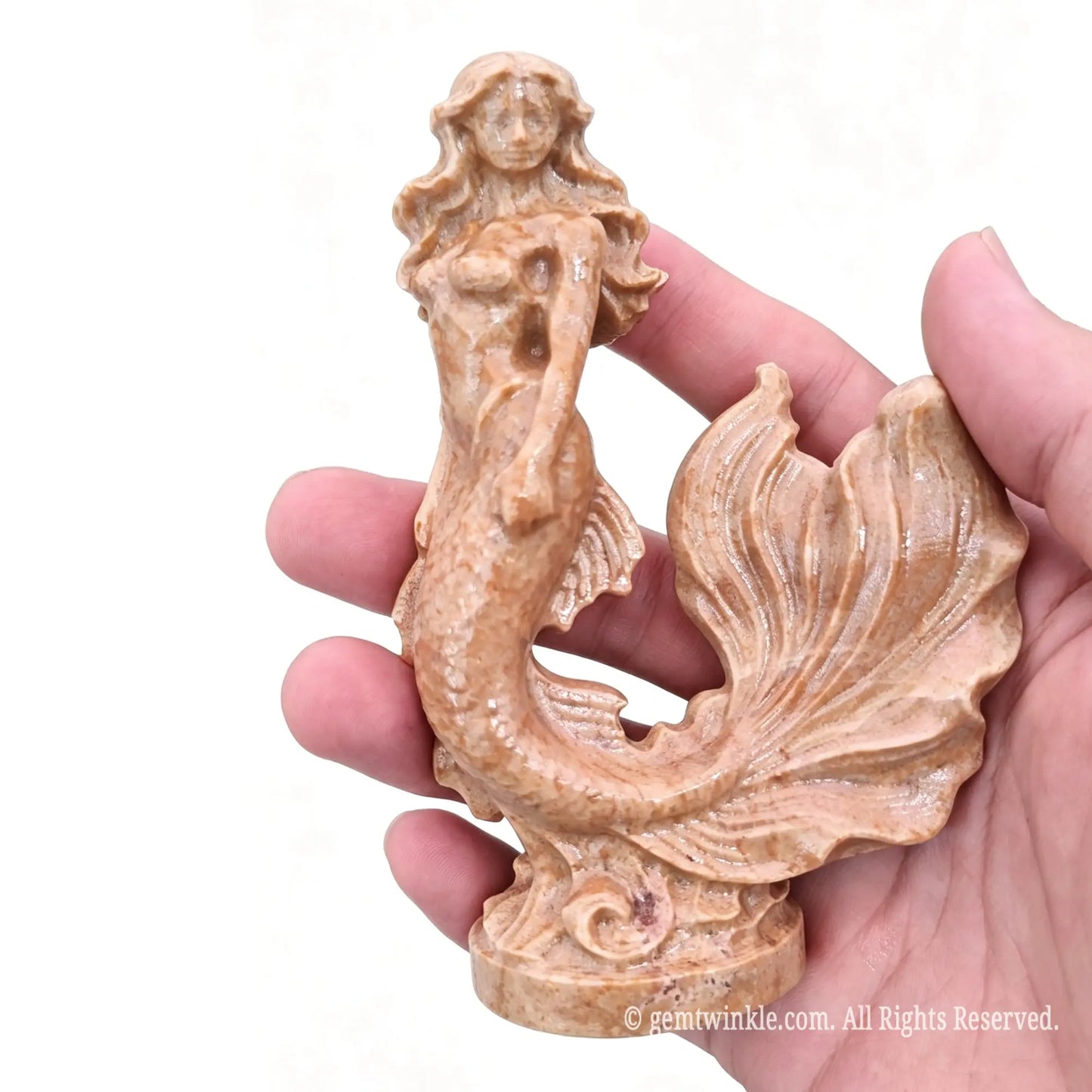 Single natural yellow stone mermaid statue 11cm height held in hand showing golden brown mineral swirls and base detail