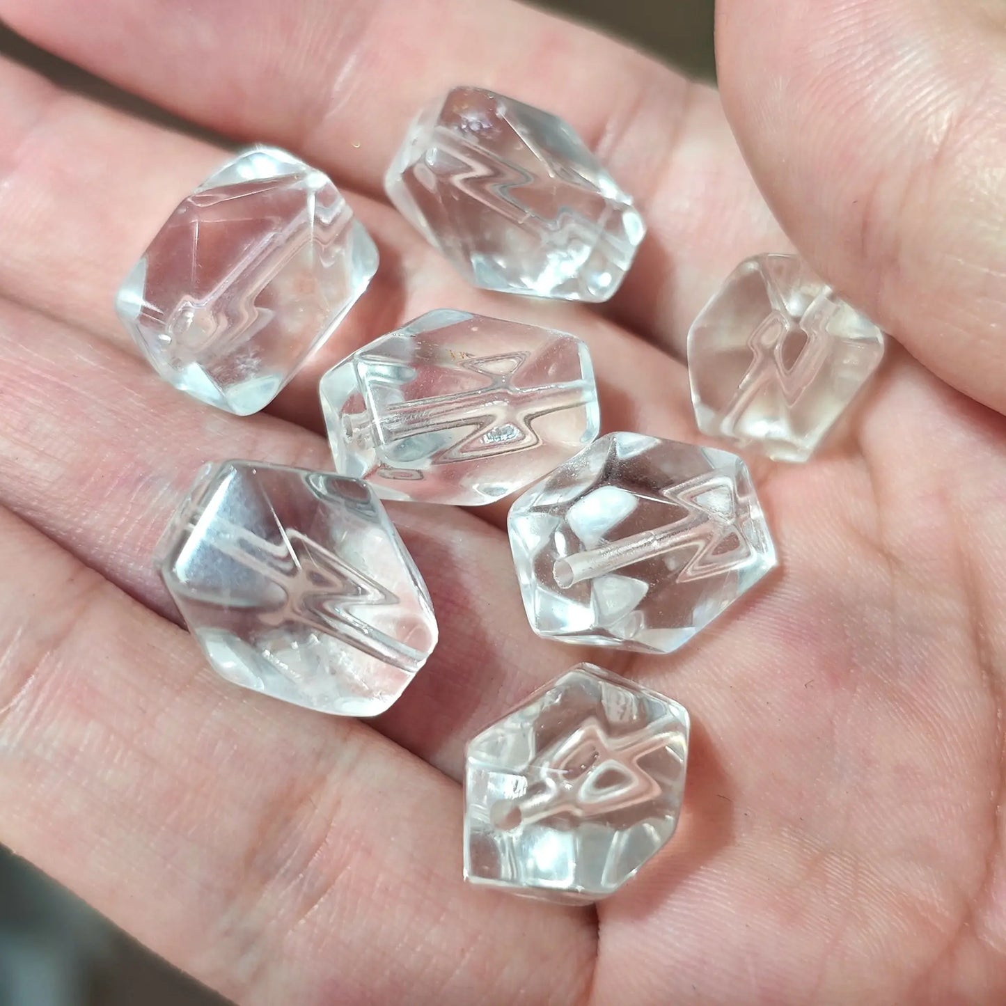 Close up view of natural rock crystal freeform beads in hand showcasing subtle wispy inclusions
