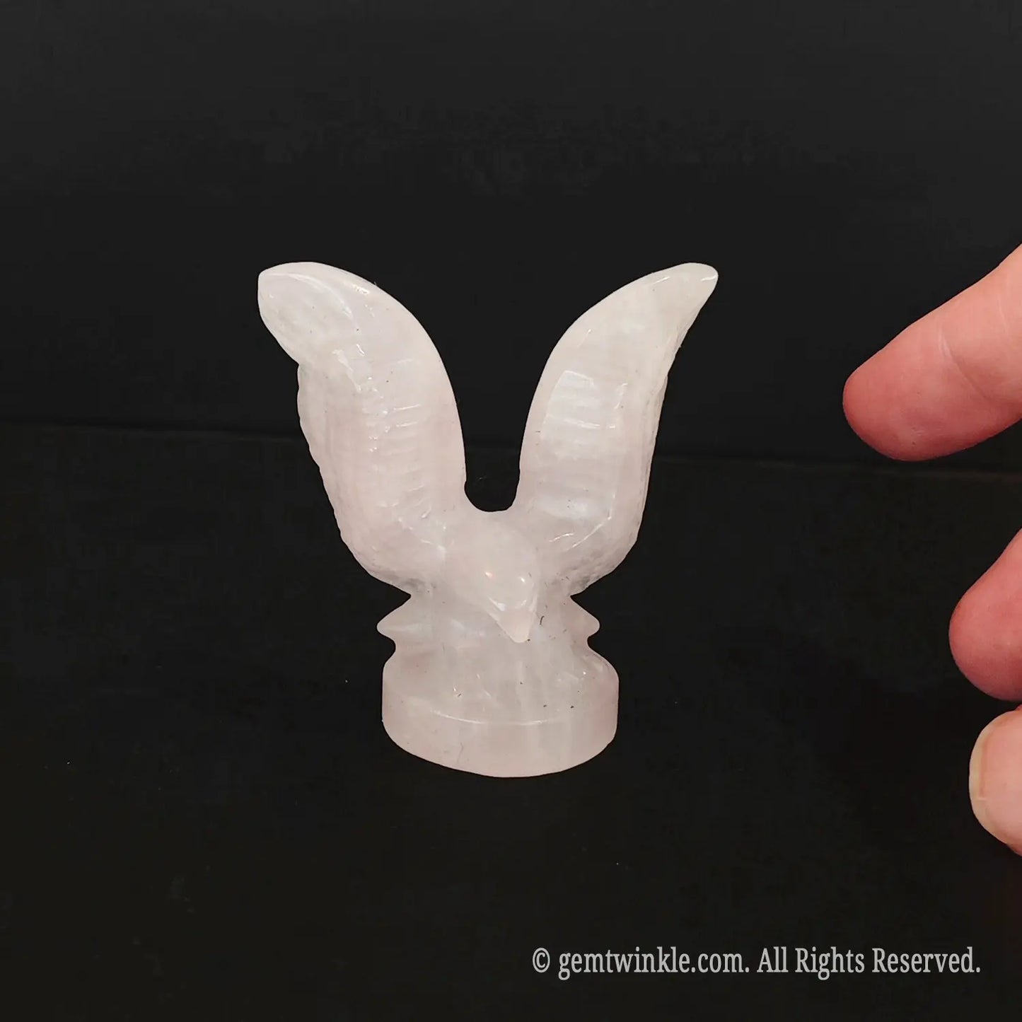 Back view of carved rose quartz eagle figurine highlighting wingspan structure