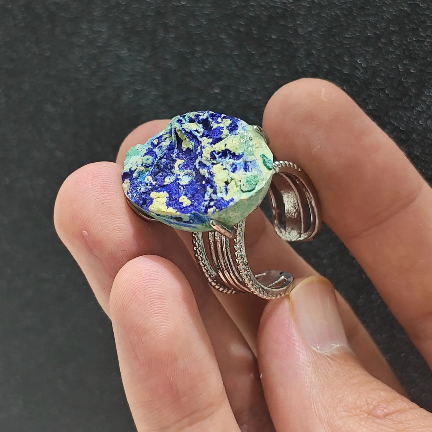 Rough gemstone azurite malachite ring held under studio lighting showing deep azure blue crystals and malachite green highlights