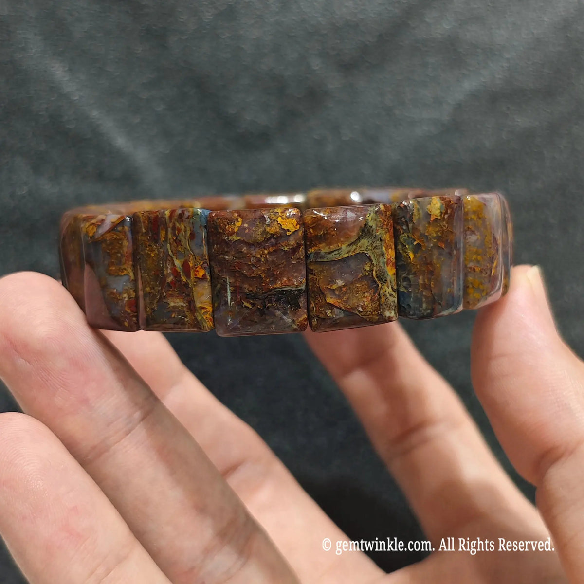 Full view of a stacked unisex fiery pietersite beaded strand displayed on hand under studio lighting