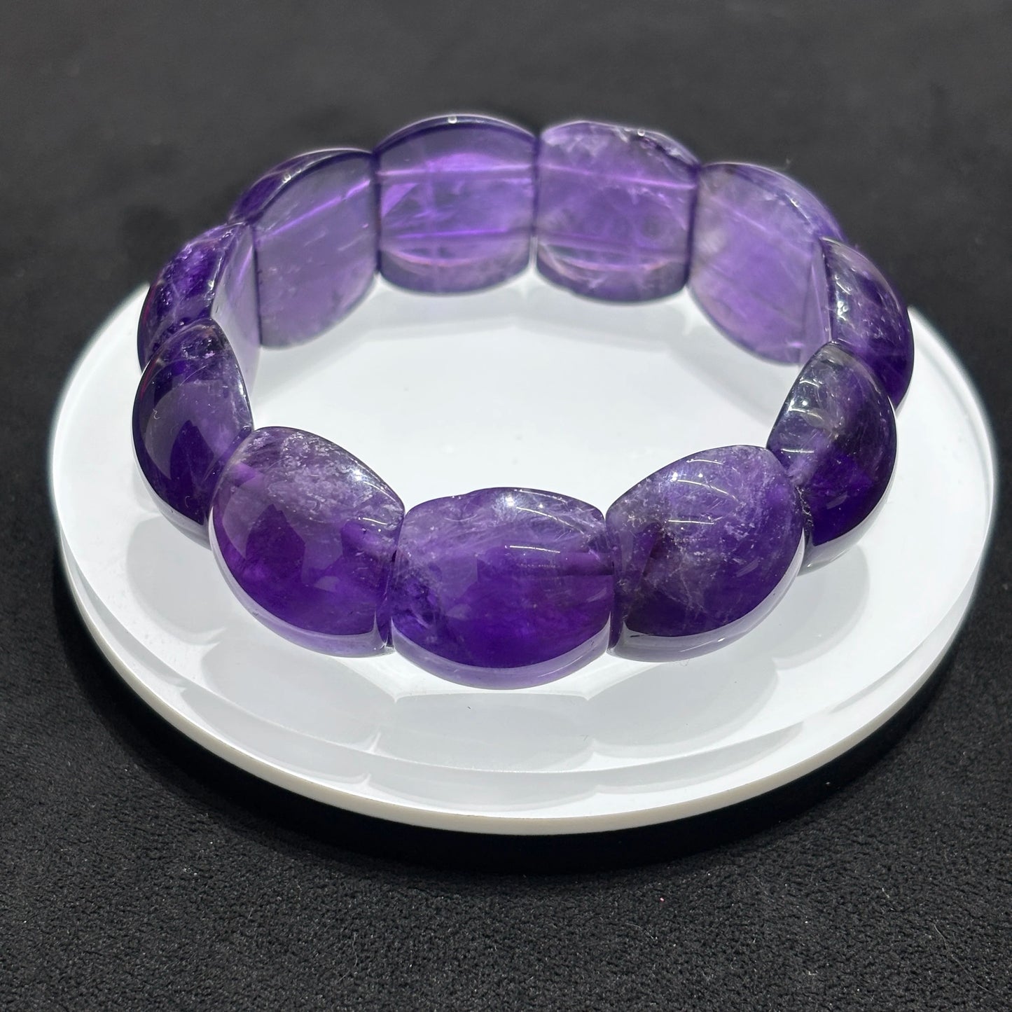 Top view of a natural amethyst rectangle bead bangle bracelet on a white dish, emphasizing the arrangement of the rectangular beads and the overall design.