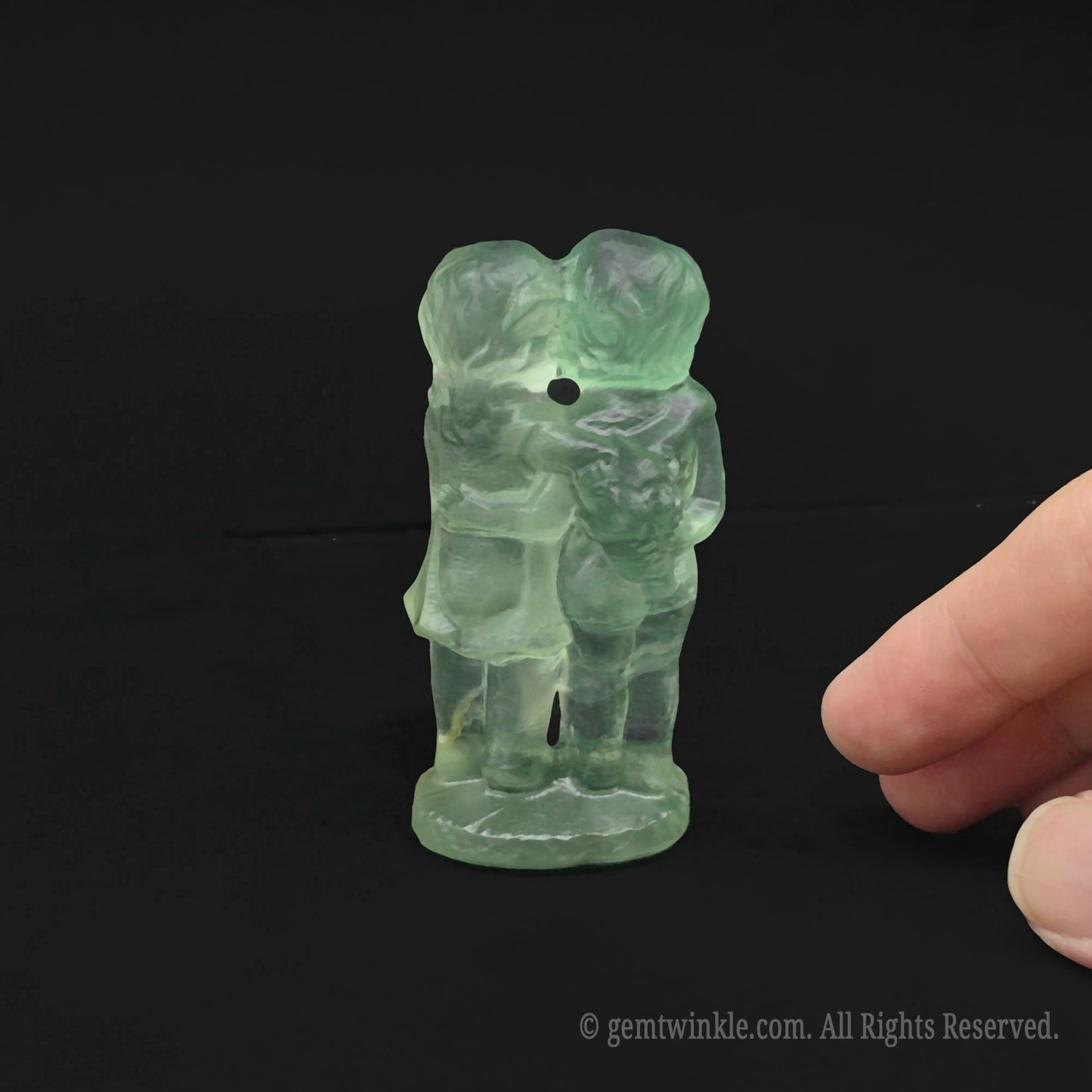 Back view of the 7cm green fluorite first kiss couple carving held in hand showcasing thickness and light clarity