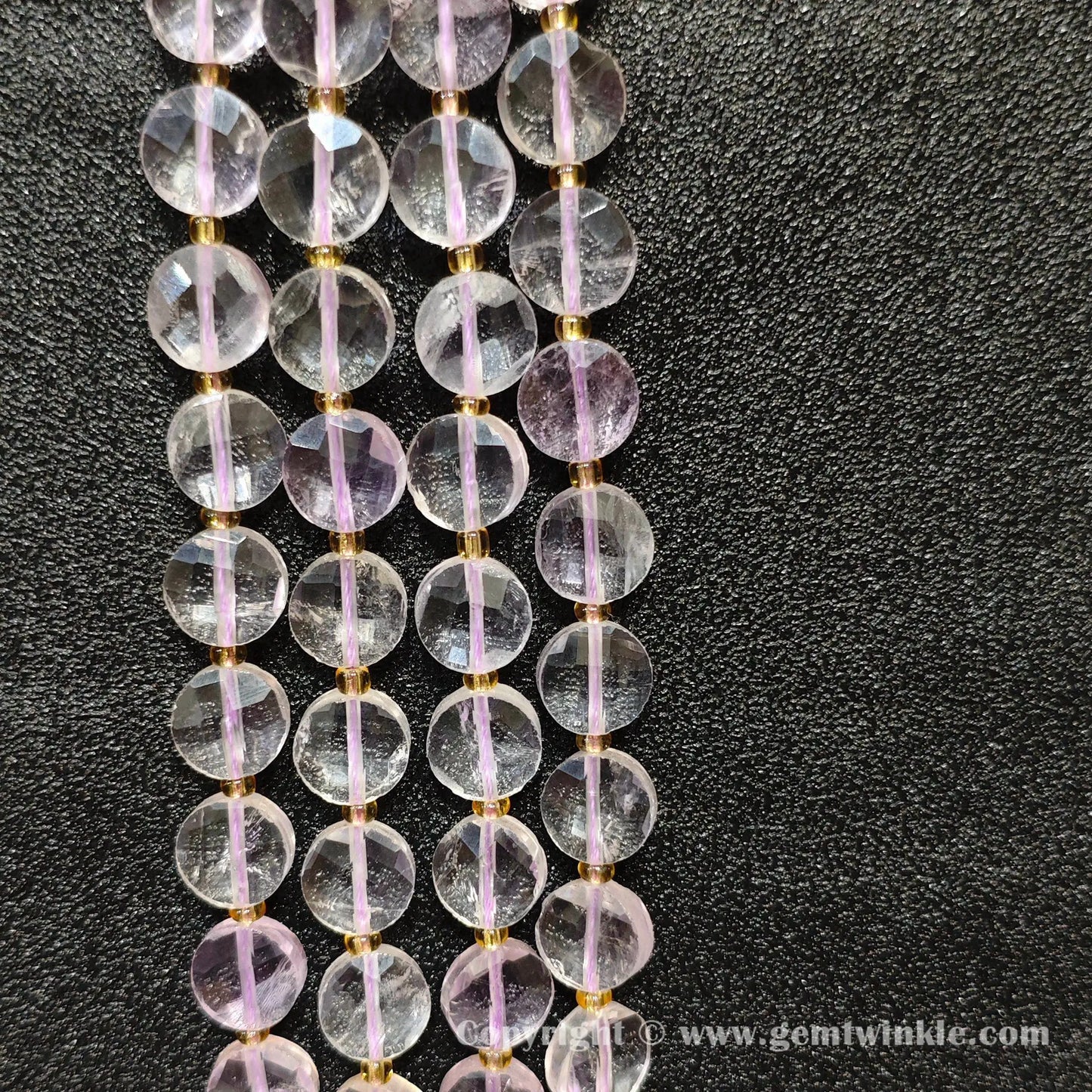 Vertical alignment of transparent pale amethyst faceted coin beads on dark background