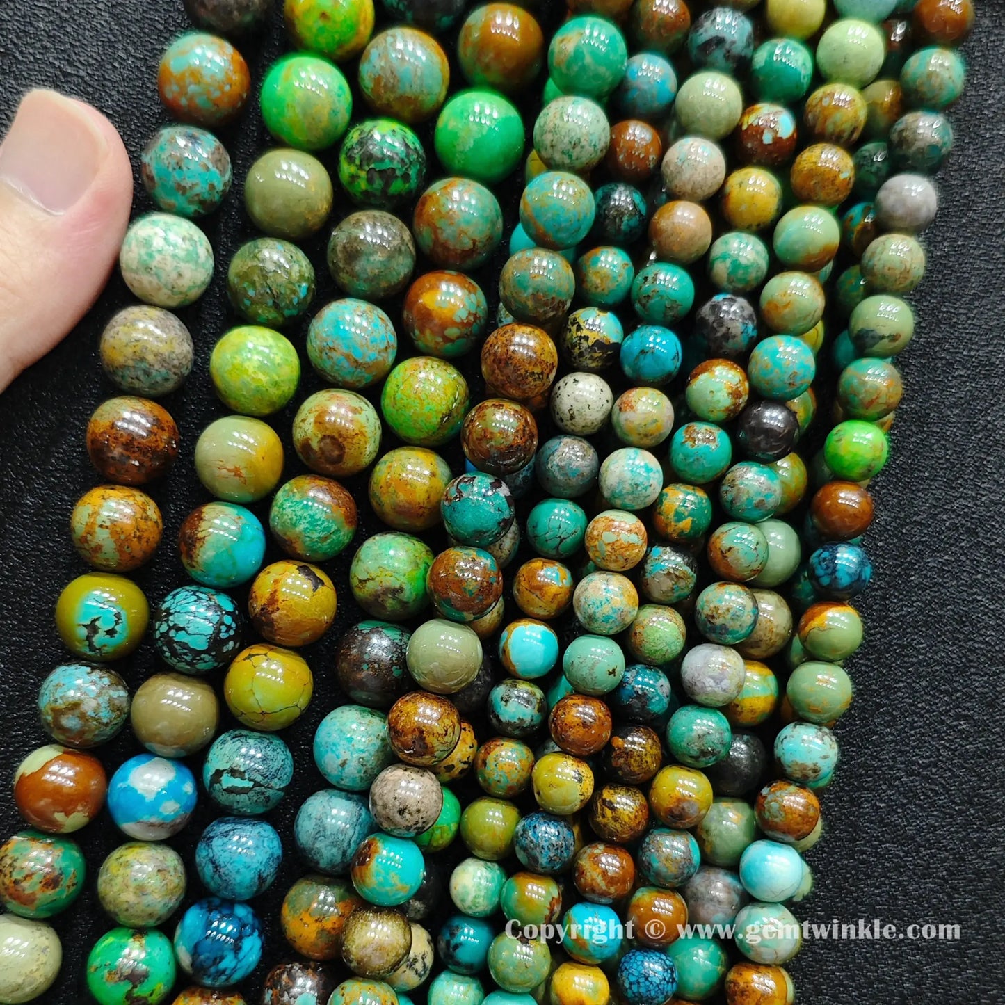 Close up view of yellowish phoenix stone round beads held on fingers for natural pattern preview