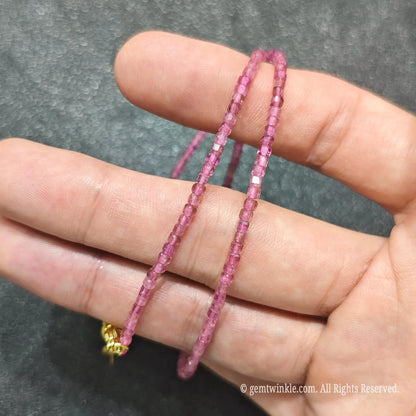 Close up of 2.5mm Pink Tourmaline square beads looped on hand highlighting gold-plated lobster clasp and extender
