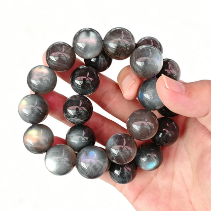 Single-strand 20mm large bead grey moonstone round bracelet held in hand showing blue optical flash