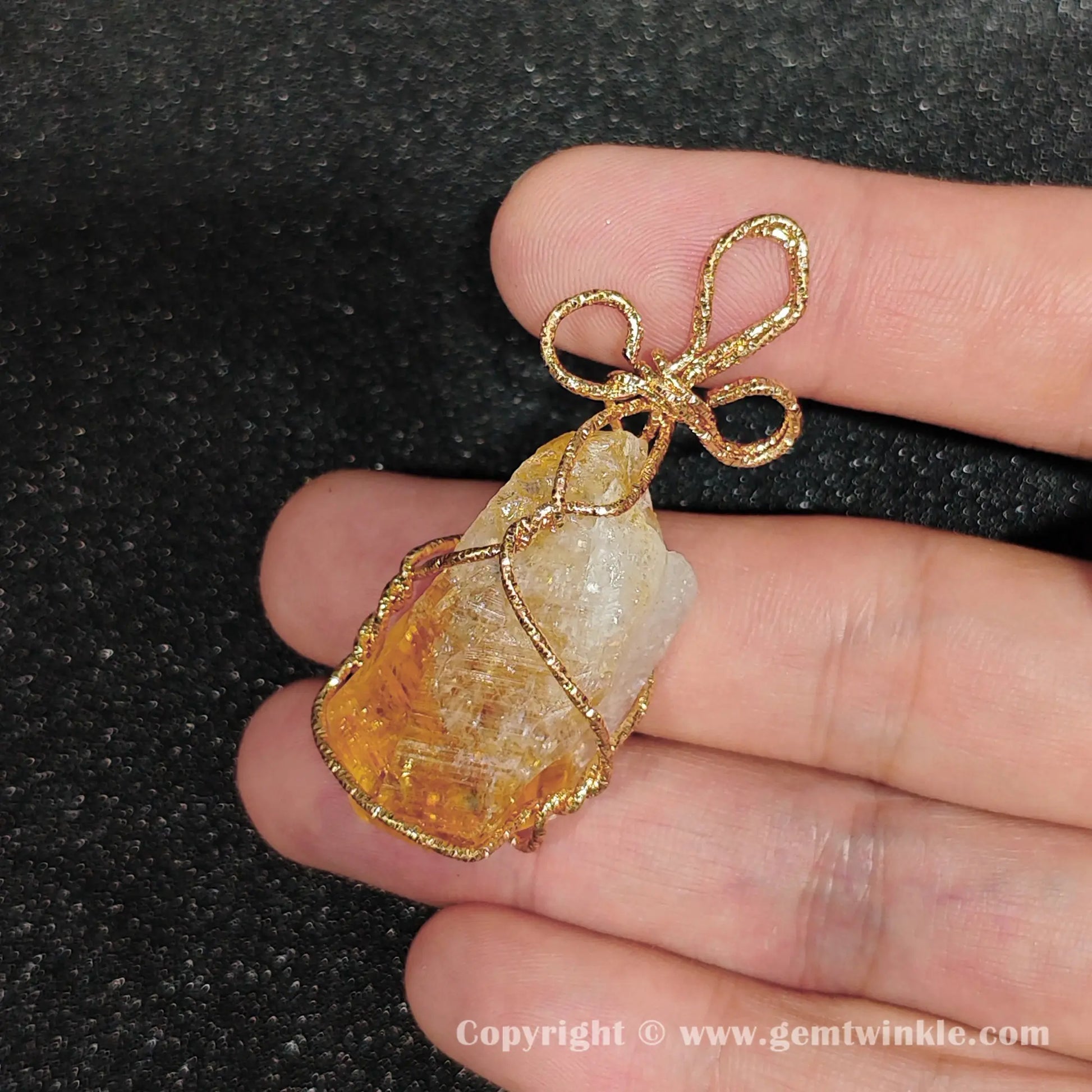 Handheld perspective of 30mm heat-altered citrine rough crystal wire wrapped component