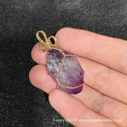 Handheld view of 30mm raw purple amethyst rough wire wrapped pendant showing dense ice crackles