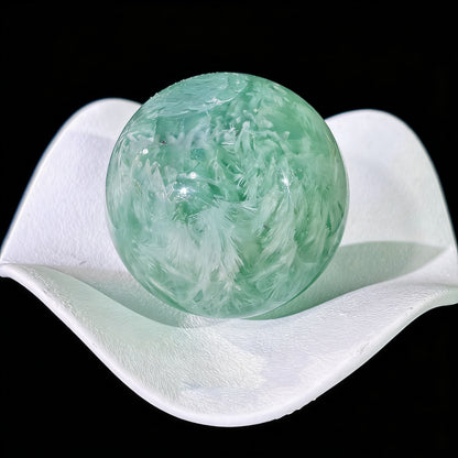 Green fluorite sphere rotated to display natural white feather inclusion pattern from all angles