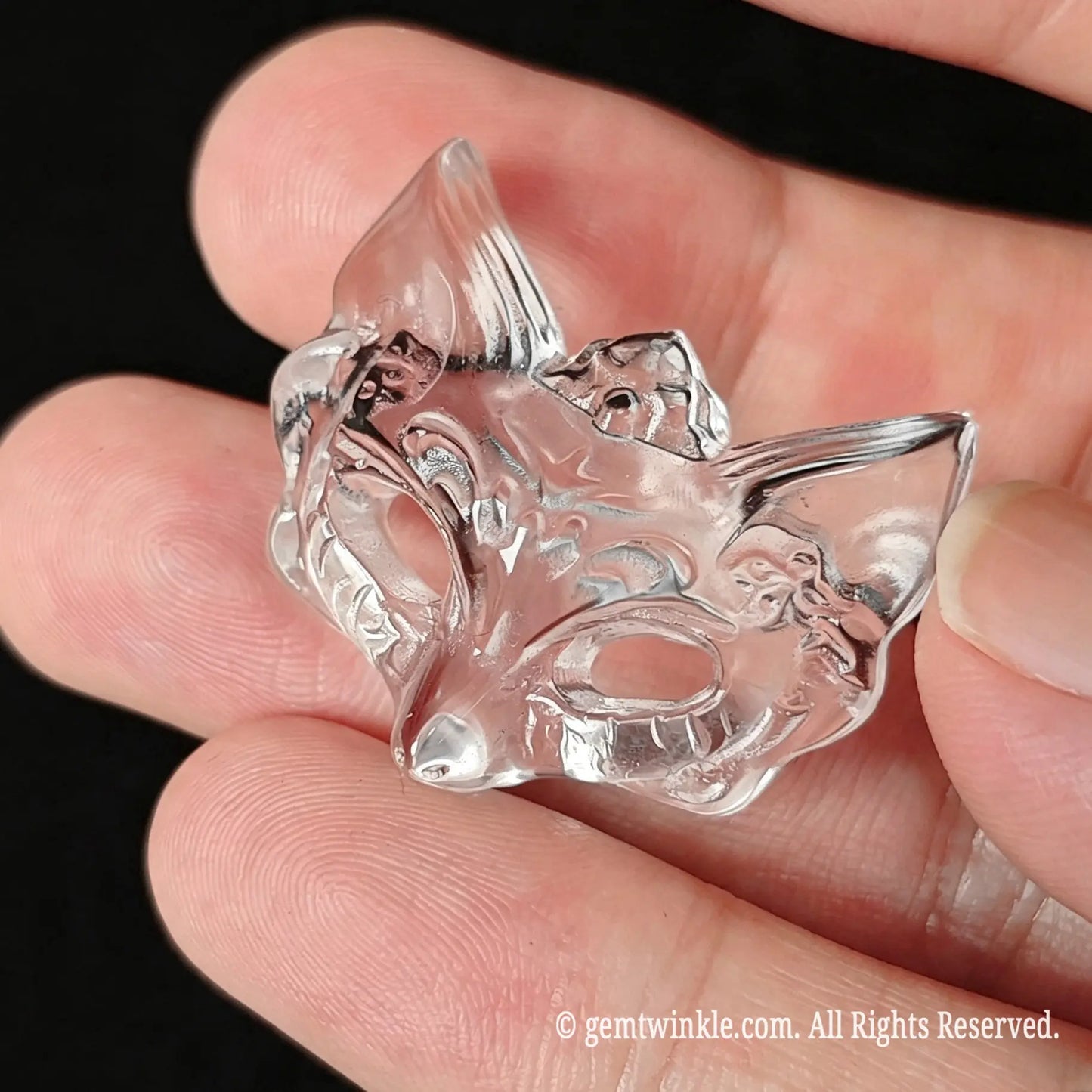 Pendant preview of carved clear quartz fox mask held in hand highlighting glass-like transparency for jewelry making