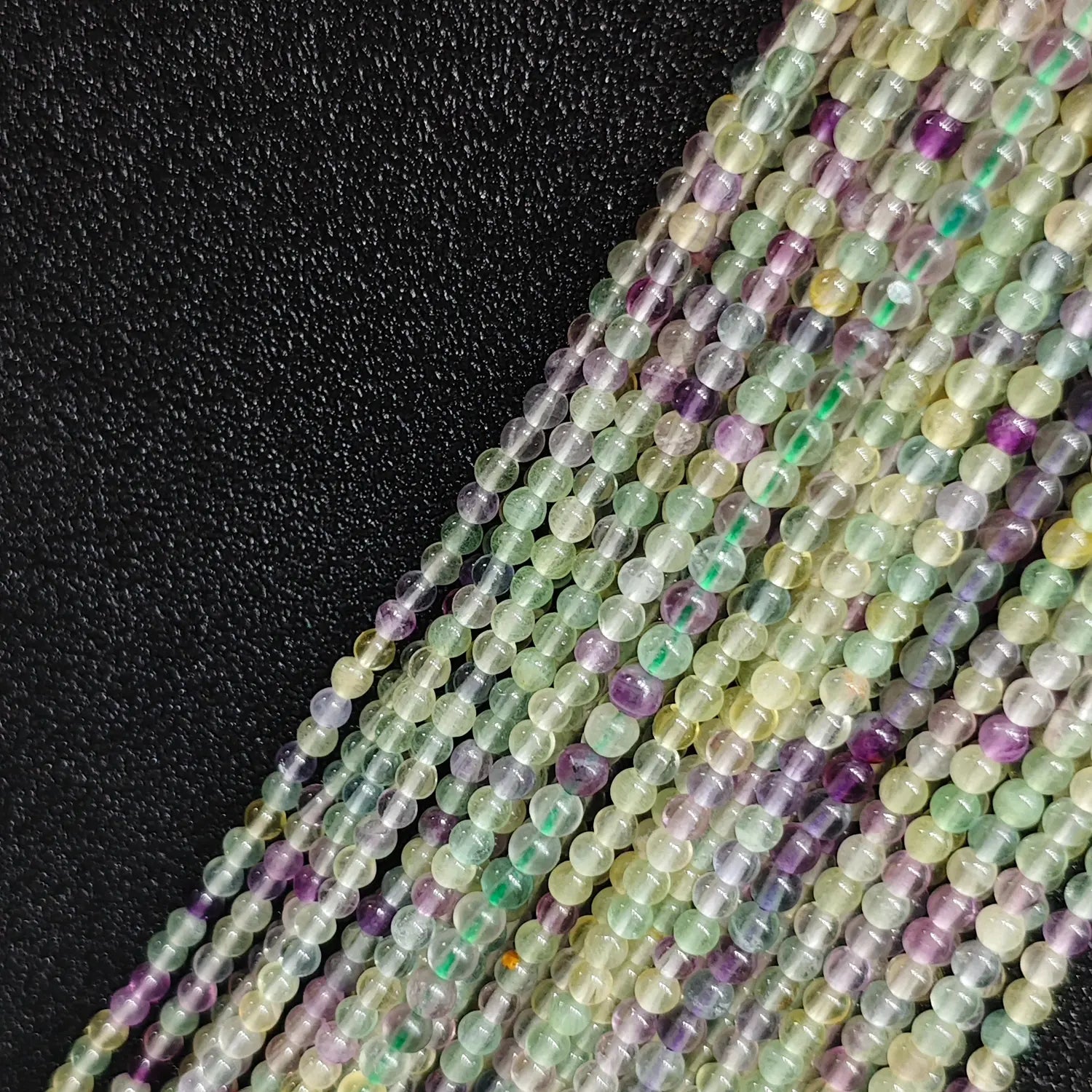 Close up of 3mm rainbow fluorite tiny beads multi color crystal strands with natural veining