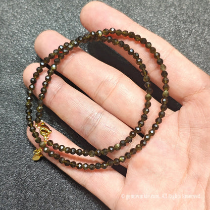 Close up of 3mm Gold Sheen Obsidian beads looped on hand highlighting gold-plated lobster clasp and extender