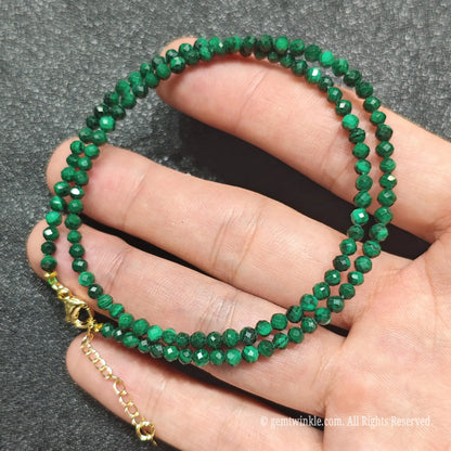 Close up of 3mm micro faceted malachite beads looped on hand highlighting gold extension chain