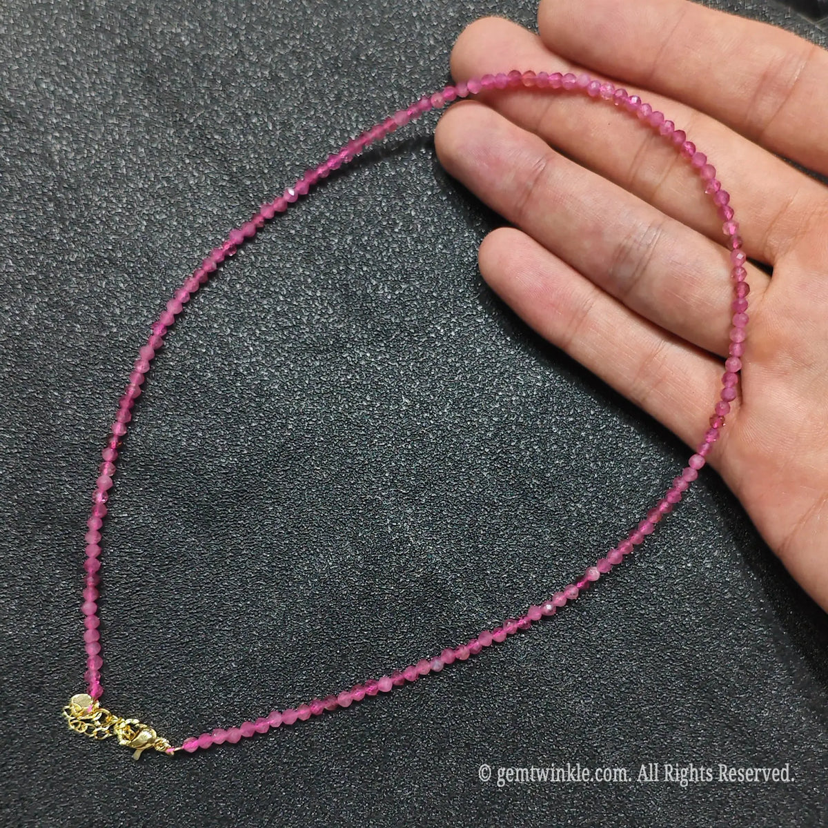 Close up of 3mm micro faceted pink tourmaline beads looped on hand highlighting gold extension chain