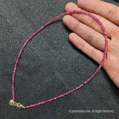Close up of 3mm micro faceted pink tourmaline beads looped on hand highlighting gold extension chain