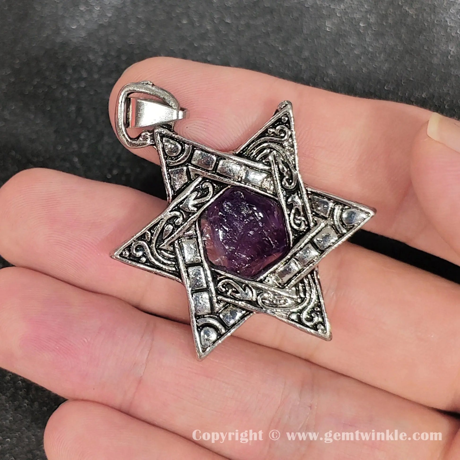Handheld view of 45mm raw amethyst hexagram star pendant showing natural crystal texture
