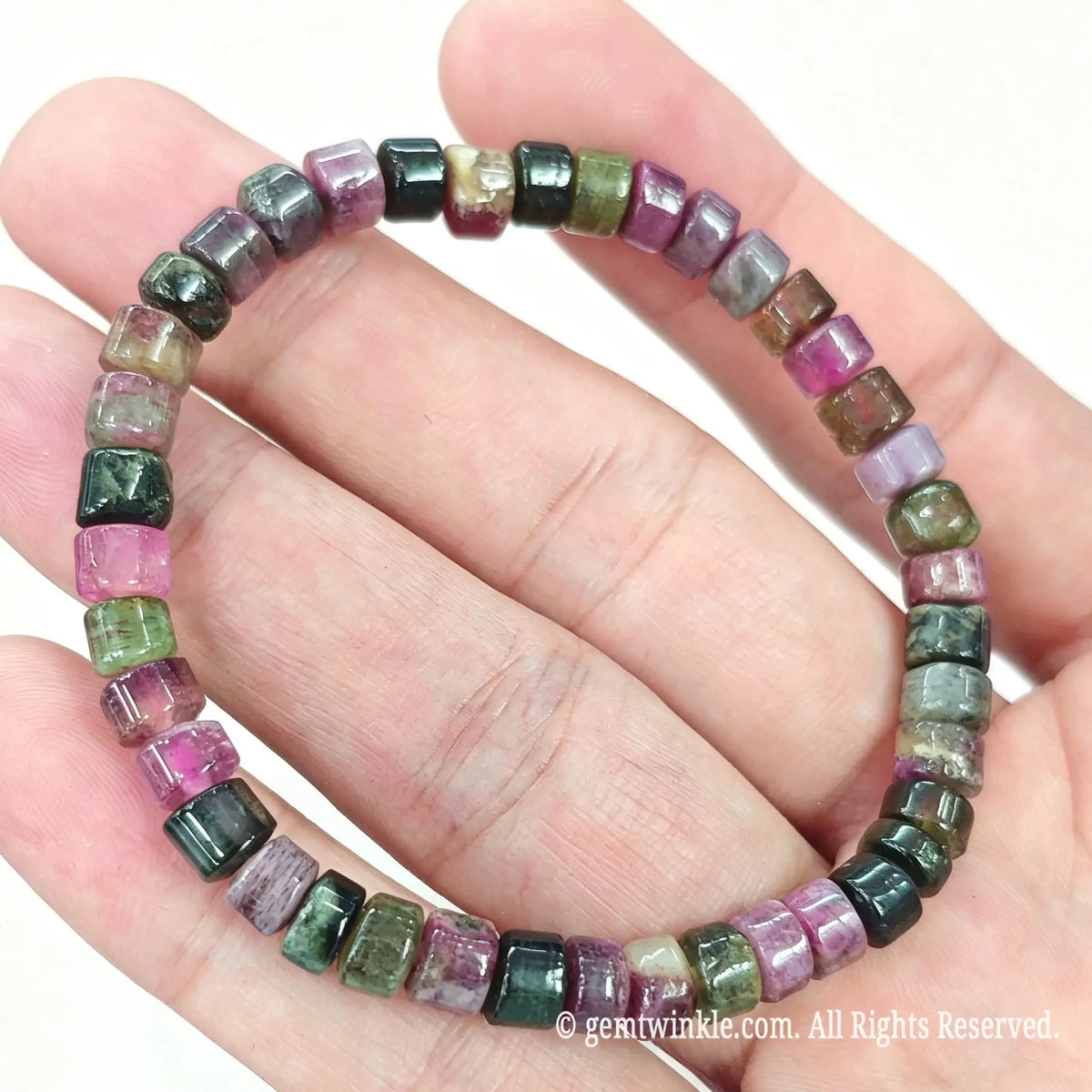 Close up view of natural tourmaline rondelle beads displaying rich magenta, green, and dark mineral tones